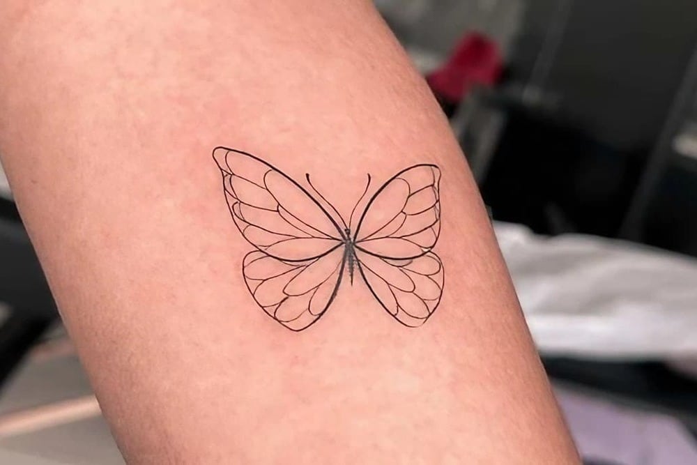 tatuaje de mariposa lineal en brazo mujer