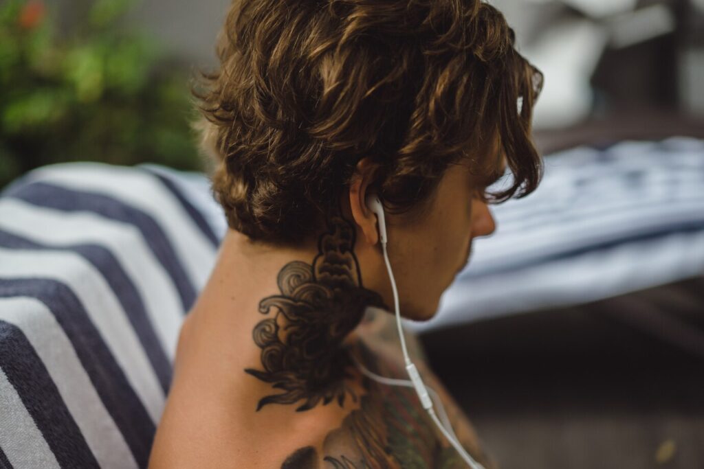joven tatuado auriculares escucha musica dibuja cuaderno
